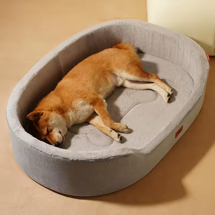 Gray oval plush pet bed with a raised wraparound edge and lowered front